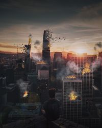 Rear view of man and cityscape against sky during sunset