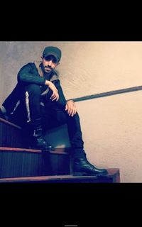 Man wearing hat while sitting on railing