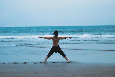 Rear view of man standing on beach against clear sky