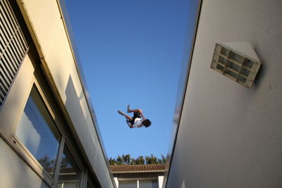 Low angle view of man jumping against building