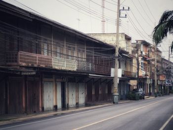 Road by buildings against sky in city