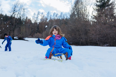 Portrait of smiling boy sitting on snow covered field