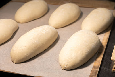 Several loaves of raw dough lie on a wooden board. craft bread before baking