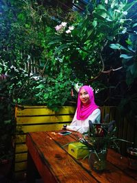 Portrait of smiling young woman sitting on tree