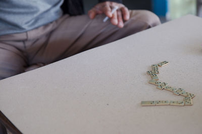 Midsection of man sitting by dominos on table