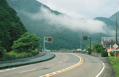 Road by trees against mountains in city