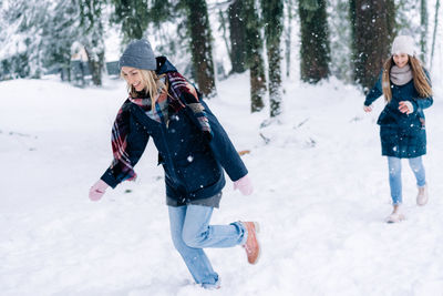 Two female girlfriends play snowballs in the park during a snowfall