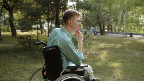 Side view of young woman sitting on field