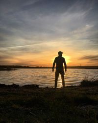 Silhouette man standing on beach against sky during sunset