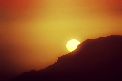 Low angle view of silhouette mountain against orange sky during sunset