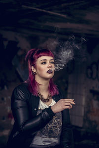Young woman smoking standing in abandoned building