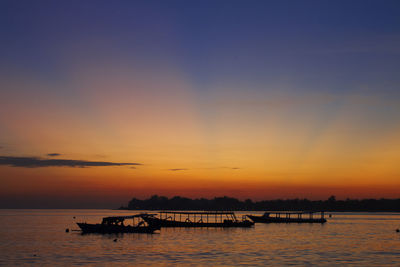 Silhouette boat in sea against sky during sunset