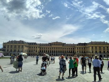 People at town square against cloudy sky