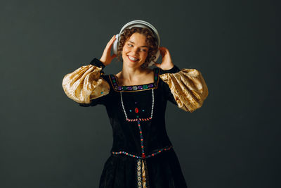 Portrait of young woman standing against black background