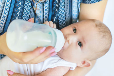 Mother feeding milk to baby girl with bottle