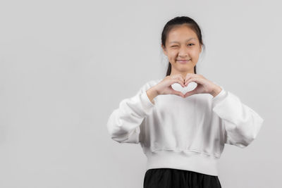 Portrait of smiling girl standing against white background