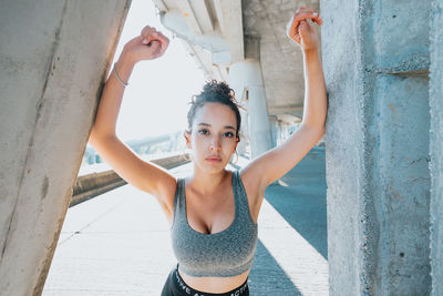 Portrait of young woman standing against wall