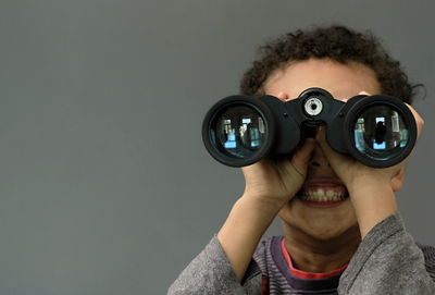 Boy looking through binoculars on grey background with people stock image stock photo