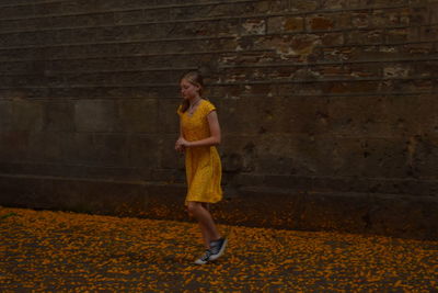 Full length of a girl standing against brick wall