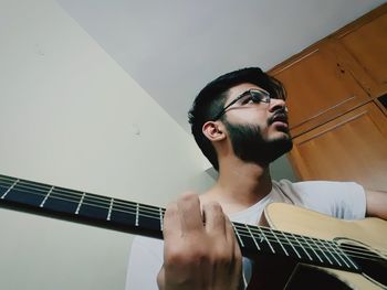 Low angle view of man playing guitar at home