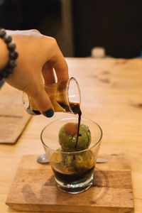 Midsection of person pouring tea in cup on table