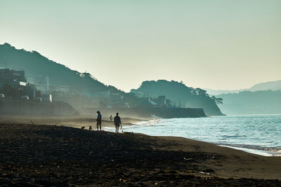 Silhouette people on beach against sky