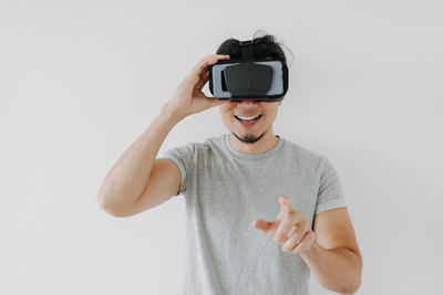 Smiling man using virtual reality simulator against white background
