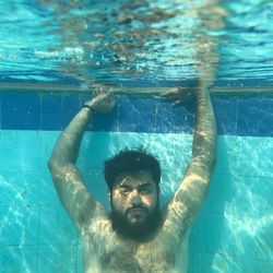 Underwater portrait of shirtless man swimming in pool