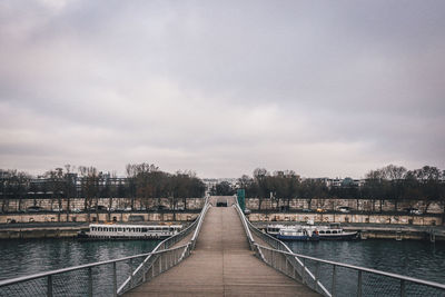 View of city at waterfront against cloudy sky