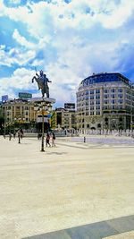 Statue in city against cloudy sky