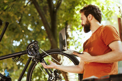 Side view of man with bicycle against trees