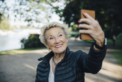 Smiling senior woman taking selfie with smart phone in park