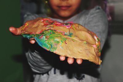 Midsection of girl holding dough with paint