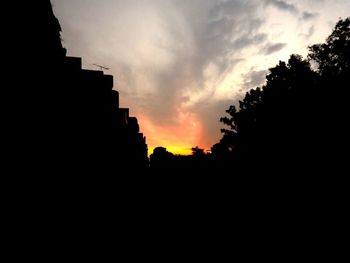 Silhouette built structures against sky at sunset