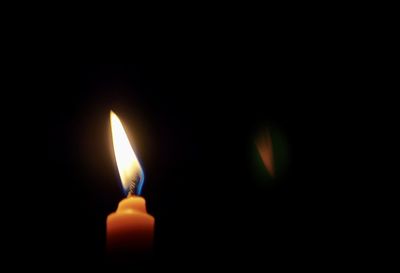 Close-up of lit candle in darkroom