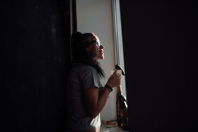 Side view of woman looking through window