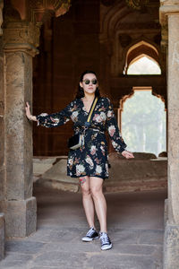Portrait of young woman standing against building