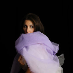 Portrait of young woman against black background