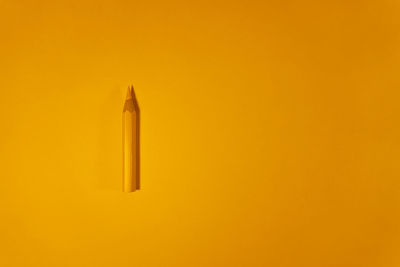 Directly above shot of yellow pencils against orange background