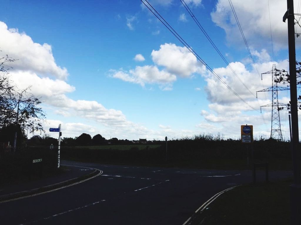 ROAD BY ELECTRICITY PYLON AGAINST SKY