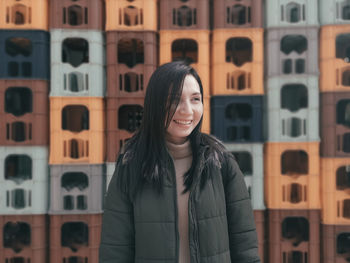 Smiling woman standing against stacked containers