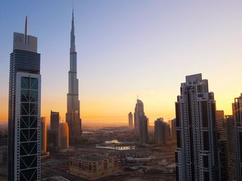 Skyscrapers in city at sunset