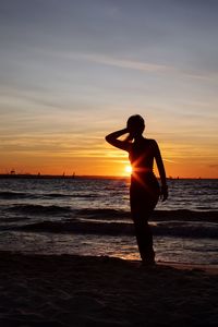 Silhouette man standing on beach against sky during sunset