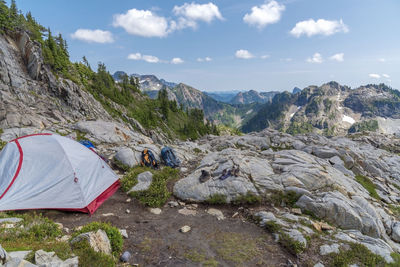 Alpine rocky mountain campsite with tent, backpacks and hiking boots.