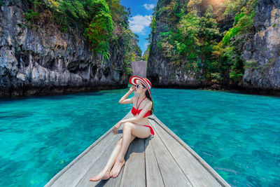 Rear view of woman sitting in boat in lake