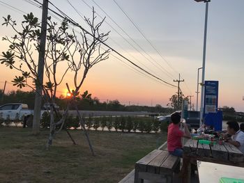 Rear view of man and woman sitting against orange sky