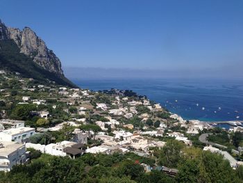 High angle view of townscape by sea against blue sky