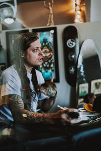 Man looking away while sitting by table