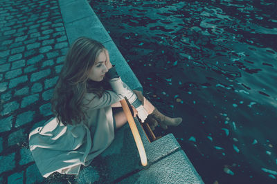 High angle view of woman sitting by canal