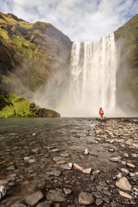 Scenic view of skogafoss waterfall against cloudy sky